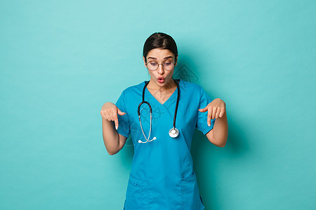 Corona病毒 大流行病和社会偏移概念 女性医生在擦拭 指向和往下看时惊艳的画面 站在蓝色背景上站立图片