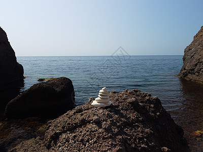 阳光明媚的日子和日落晴朗的天空在海滩上平衡的鹅卵石金字塔 背景上的金色海散景 有选择的焦点 海滩上的禅石 冥想 水疗 和谐 平静图片