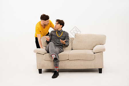 两个人坐在沙发上交流 三个年轻朋友的肖像花时间坐在小沙发上 看着白色背景中突显的相机背景图片
