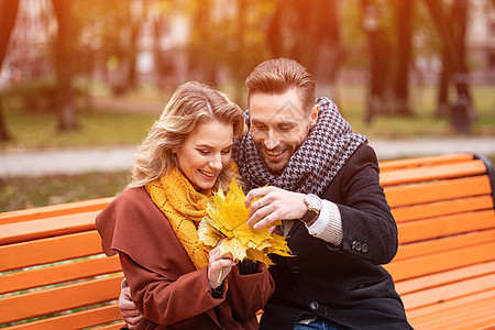 年轻的拥抱幸福浪漫的情侣穿着外套和围巾坐在公园的长椅上轻轻拥抱 一对浪漫的情侣坐在公园的长椅上拥抱 爱情故事女性男朋友男人男性朋图片