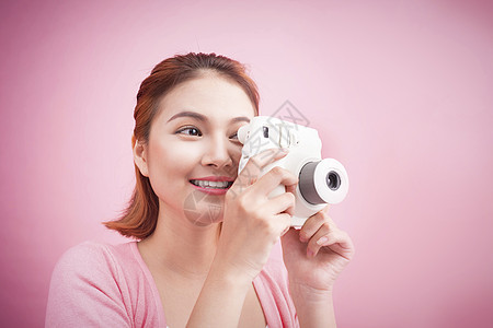 年轻女人用照相机拍照片粉色爱好相机女性成人女孩摄影相片摄影师女士图片