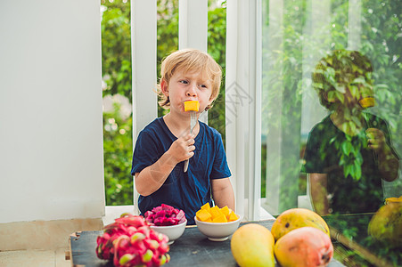 小可爱男孩在阳台上吃芒果异国温泉公园婴儿乐趣喜悦情调海滩热带橙子图片