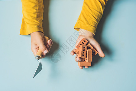 特写孩子的手在桌子上玩真正的小粘土砖 蹒跚学步的孩子玩得开心 用真正的小粘土砖搭建 早期学习 开发玩具 建设理念图片