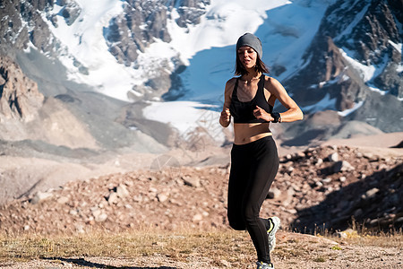 女孩在雪山的足迹上奔跑女士冰川运动员运动身体女性慢跑者踪迹岩石平衡图片