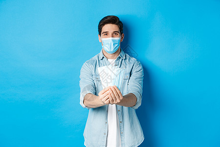 Corona病毒 检疫和社会偏移概念 年轻人用医疗面具防止病毒传播 站在蓝色背景下站立 在蓝底促销闲暇口罩商业男性广告情绪成功成图片