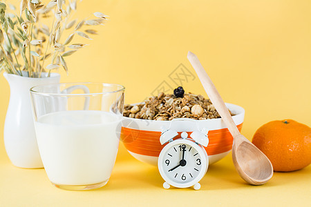 健康健康的早餐 碗中的烤面包 牛奶杯 橙色和黄色背景的闹钟;以及图片