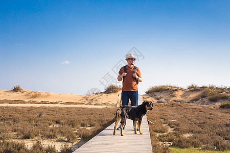 男人带着狗走在一条通向美丽风景的道路上友谊忠诚背包团体闲暇农田活动乡村成人远足者图片