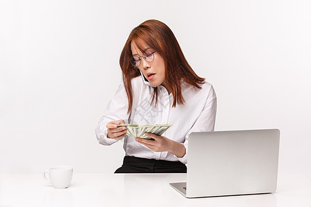 职业 工作和女企业家的概念 特写 忙碌严肃的亚洲女商务人士 办公室女士坐在桌前 数钱 用手机聊天 用笔记本电脑写作图片