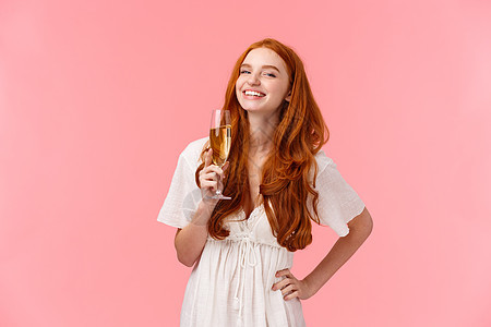 幸福 自信和庆祝的概念 快乐而无忧无虑的迷人红头发 b-day 女孩喝着香槟笑着 玩得开心 享受派对 站在粉红色的背景上图片