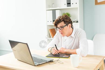 商业 设计和人的概念     穿着白衬衫的英俊青年男子 在木制桌上使用图形片板办公室戏服药片文件夹椅子工人钱包邮政幽默夹克图片