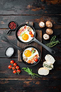 炸鸡蛋 培根和蔬菜 用铁煎锅制成的炒烤炉;在旧黑木板桌背景上 顶层视野平铺图片