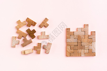 组织和秩序 木制拼图块正确堆叠 杂乱无章地散落在粉红色背景中图片