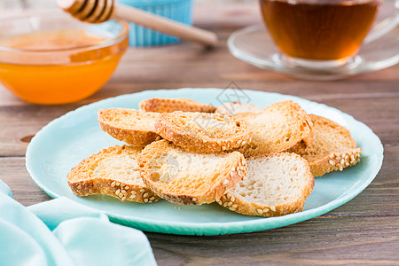 小面包面包烤面包 放在木制餐桌上的盘子上 早餐用茶和蜂蜜图片