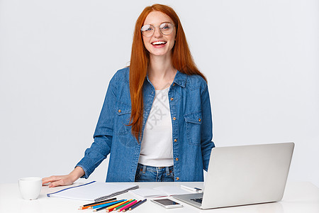 教育 工作和自由职业者的概念 迷人的魅力红发女性数字游牧者 远程工作的设计师 创建设计项目 站在桌边 拿着笔记本电脑 彩色铅笔图片