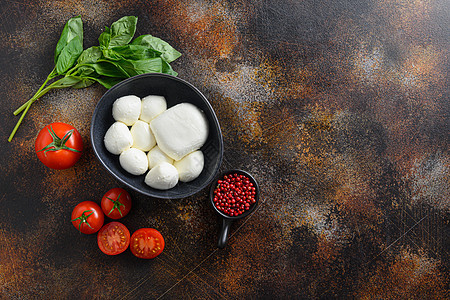 黑碗里放着罗勒和西红柿的美味马苏里拉奶酪 沙拉卡普雷塞的配料 在老土气金属背景 Caprese 沙拉配料 选择性的焦点 文本的顶图片