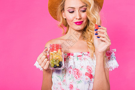 以粉红背景将新鲜水果装在瓶子里的年轻女子特写肖像食物玻璃果汁潮人女性营养别针工作室青年排毒图片
