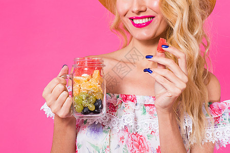 以粉红背景将新鲜水果装在瓶子里的年轻女子特写肖像果汁工作室乐趣饮食饮料食物女孩营养女性排毒图片