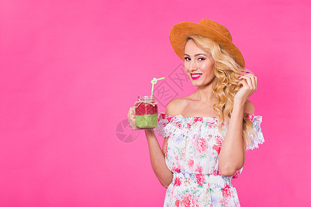 年轻女子在粉红背景和复制空间上拿着并喝着美味的绿色清凉冰淇淋奶昔的肖像营养排毒玻璃果汁饮料青年工作室稻草女性潮人图片
