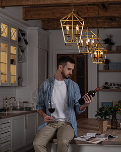 一个穿着蓝衬衫和黑米裤的胡子男坐在厨房的桌子上图片