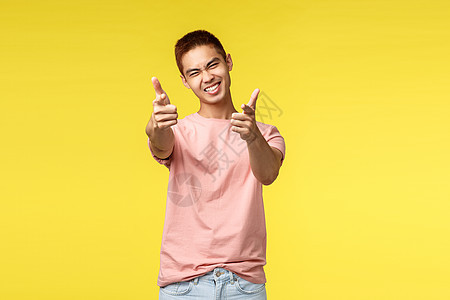 生活方式 旅行和人们的观念 你这个摇滚人 热情帅气的亚洲帅哥用手指指着镜头 微笑 挑选或招募到他的团队的肖像 黄色背景技术广告潮图片
