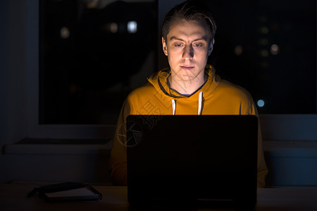 男人晚上在笔记本电脑上工作房间男性监视器职场学习电话窗户展示商业办公室图片