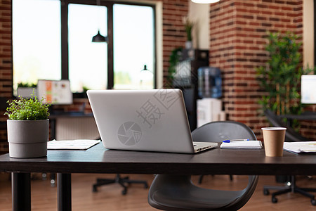 用笔记本电脑 咖啡杯和植物锅贴近办公桌图片