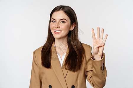 公司女性的肖像 女销售员展示四指和微笑 站在白色背景上的西装图片