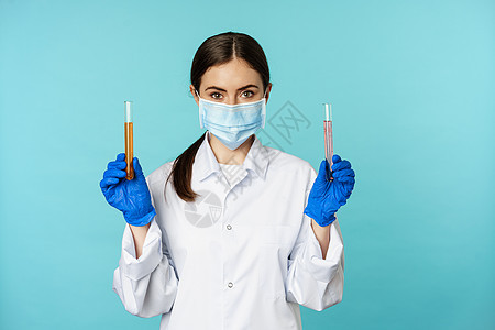 年轻女医生 做研究的实验室工作人员 拿着试管 戴着医用面罩和橡胶手套 蓝色背景的形象女士横幅擦洗专家成人女性医院临床医师职业图片