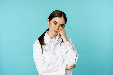 身穿蓝底白外套的年轻女医生 穿着蓝色背面白大衣 脸色平淡沉闷无聊无趣实习生横幅工作室广告保健女士卫生医师护士黑发图片