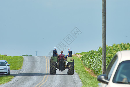 阿米什男孩和女孩少年骑着旧拖拉机Tru农场图片