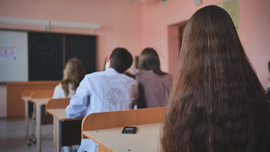 上课时课桌边的班级11年级学生 是俄罗斯学校的学生中学孩子童年女孩们老师女孩帮助桌子青少年时间图片