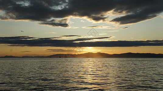 海边美丽的橙色日落 远处的岛屿夕阳太阳天空波浪图片