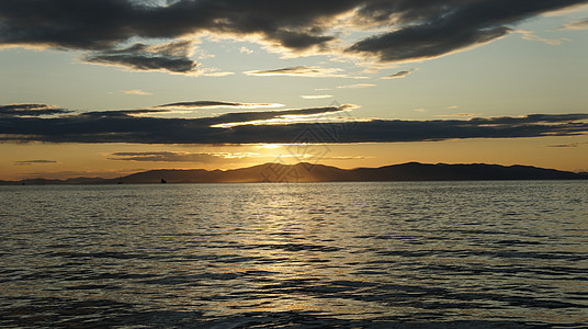 海边美丽的橙色日落 远处的岛屿天空太阳夕阳波浪图片