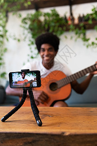 微笑的年轻非洲裔美国人用手机录制吉他在线课程 选择性专注于电话 垂直的图片