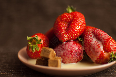 圆盘上红色成熟的草莓 配有几块甘蔗糖和融化的白巧克力美味营养浆果甜点食物乡村果味盘子烹饪木头图片