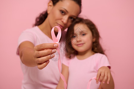 专注于一条长长的粉红色缎带 一头无尽的末端在模糊的两代漂亮女人妈妈和女儿的手中 表达了对癌症患者和幸存者的支持和声援图片