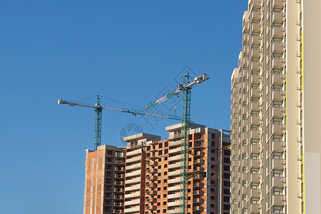 新建筑施工背景清澈的蓝天 多层房子 抵押 塔式起重机施工现场建筑公司物业投资建设房地产公寓建设建设图片