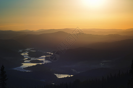 山间金色晚霞 山峦的深色剪影 薄雾中的金光 蓝天的云朵 谷底河水的倒影图片