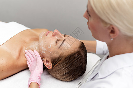 女性美容清洁剂和润滑剂将病人的皮肤用在温泉沙龙图片