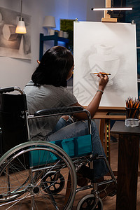 残疾年轻女艺术家在画布上画花瓶图片