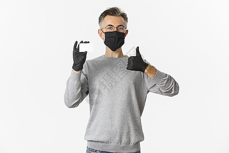 covid19 的概念 社会距离和生活方式 满意的中年男子戴着医用口罩 手套和眼镜 推荐银行 出示信用卡和竖起大拇指商业工作室社图片