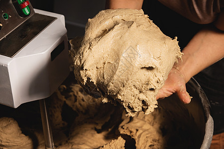 在一家面包店生产面团搅拌厂背景下 紧贴面包师女性手握着面粉图片