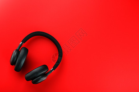 红色背景顶视图上的黑蓝牙耳机 DJs 的在小耳机潮人帽子电子产品立体声耳朵听力娱乐打碟机插图工作室图片