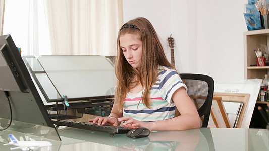 幼儿在电脑打字在线功课前坐在书桌前的计算机打字图片