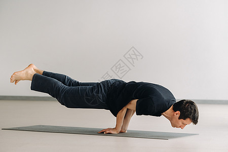 一个穿黑色T恤火车的男人 躺下在健身房做伸展成人活动运动垫运动员姿态姿势瑜伽衣服肌肉身体图片