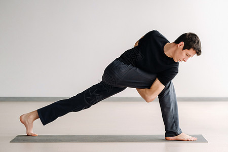 一个穿黑色T恤的男子 站立起来在健身房伸展运动运动垫数字运动装力量身体姿势护理衣服姿态图片