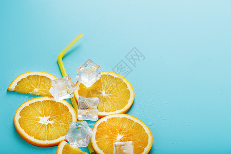橙色切片和冰块 以鸡尾酒的形状 在蓝色背景上的稻草水果果汁液体立方体饮料食物酒吧酒精橙子营养图片