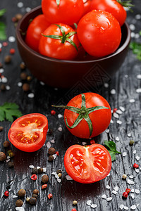 黑色背景的新鲜鲜切樱桃番茄 配有香料粗咸盐和草药食物藤蔓叶子石头营养桌子蔬菜石板香菜烹饪图片