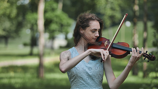 有个年轻女孩在公园里拉小提琴寂寞文化演员露天节日孤独音乐会城市艺术家乐器图片