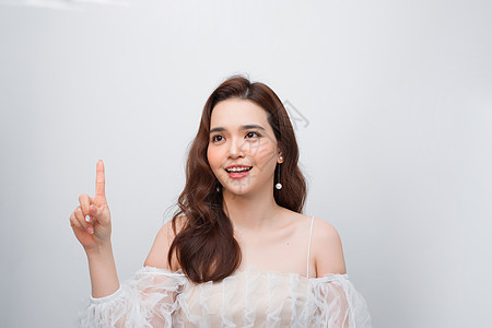 年轻亚洲女士对具有广告复制空间的无形产品充满活力地指向上方女孩手指商业女性微笑白色图片